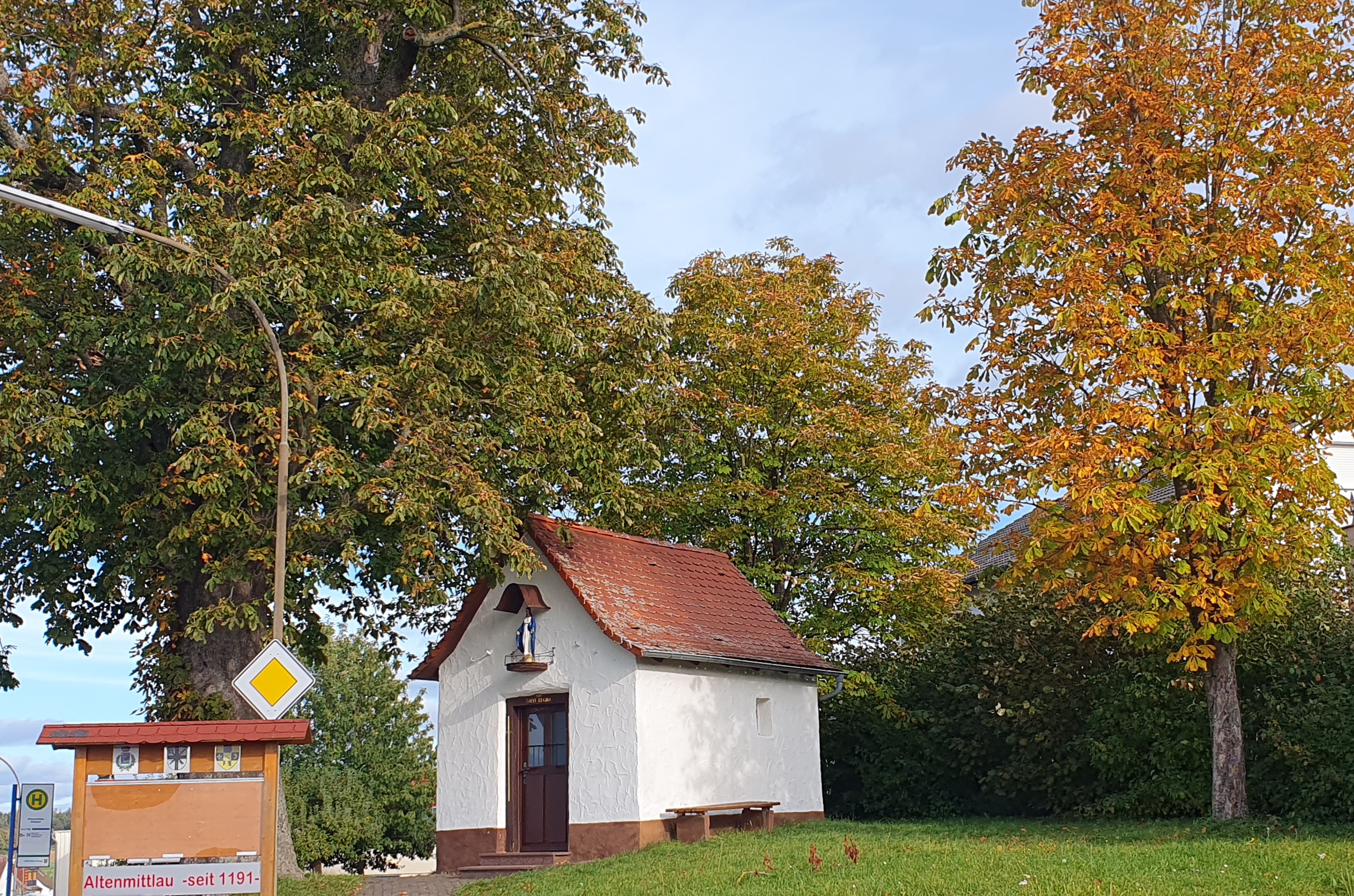 Kleines Häuschen auf einer Wiese zwischen Bäumen
