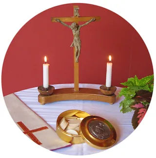 Ein Kreuz mit Korpus, rechts und links davon entzündete Kerzen, davor eine Hosteienschale