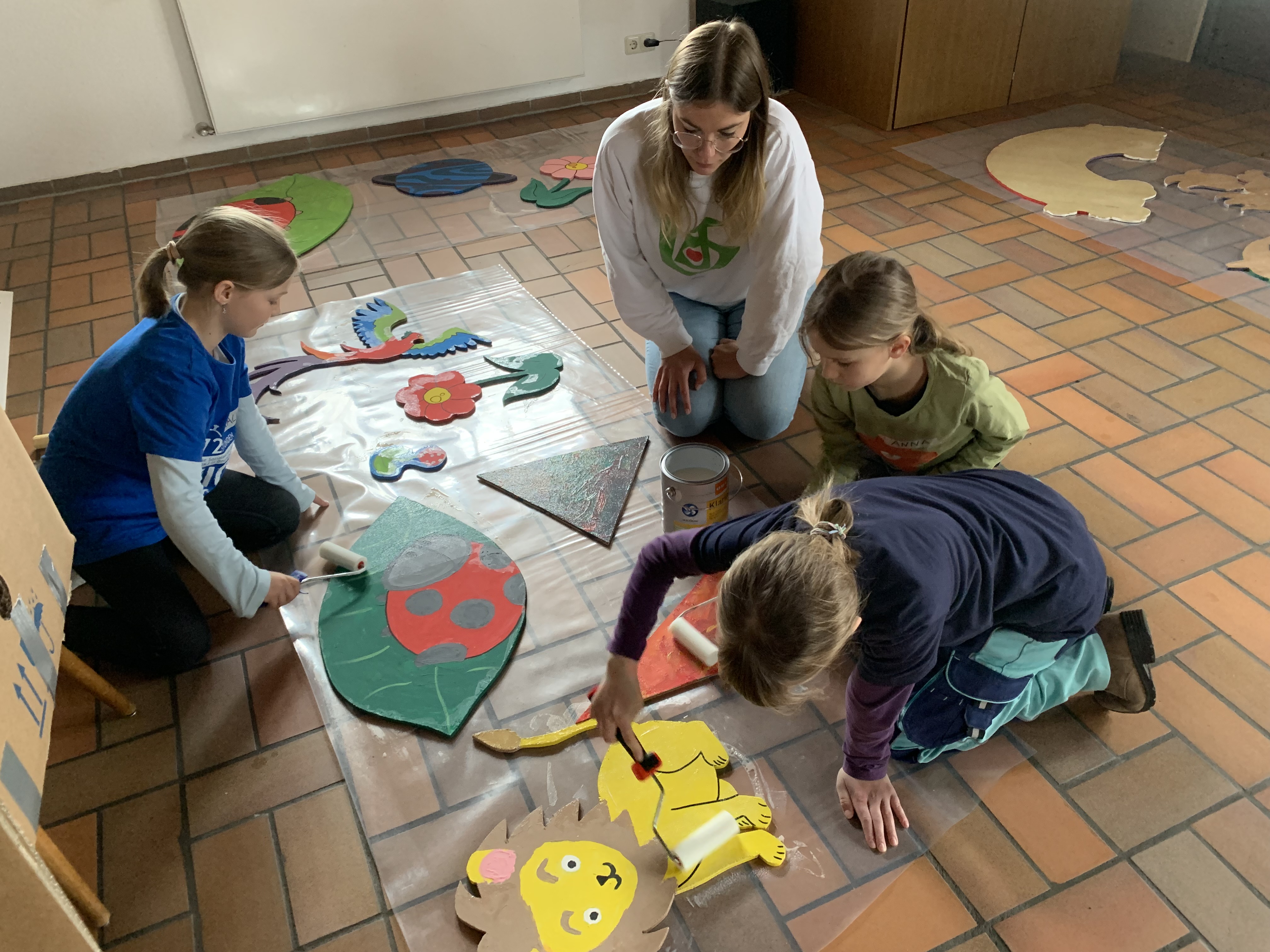 Kinder sitzen auf dem Boden und malen Tiere an.