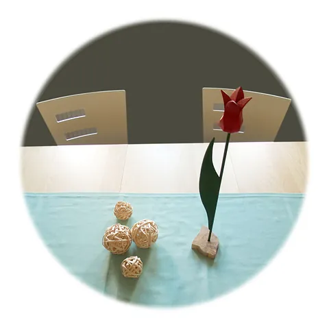 Zwei Stühle stehen am Tisch, der mit einer Holzblume dekoriert ist.