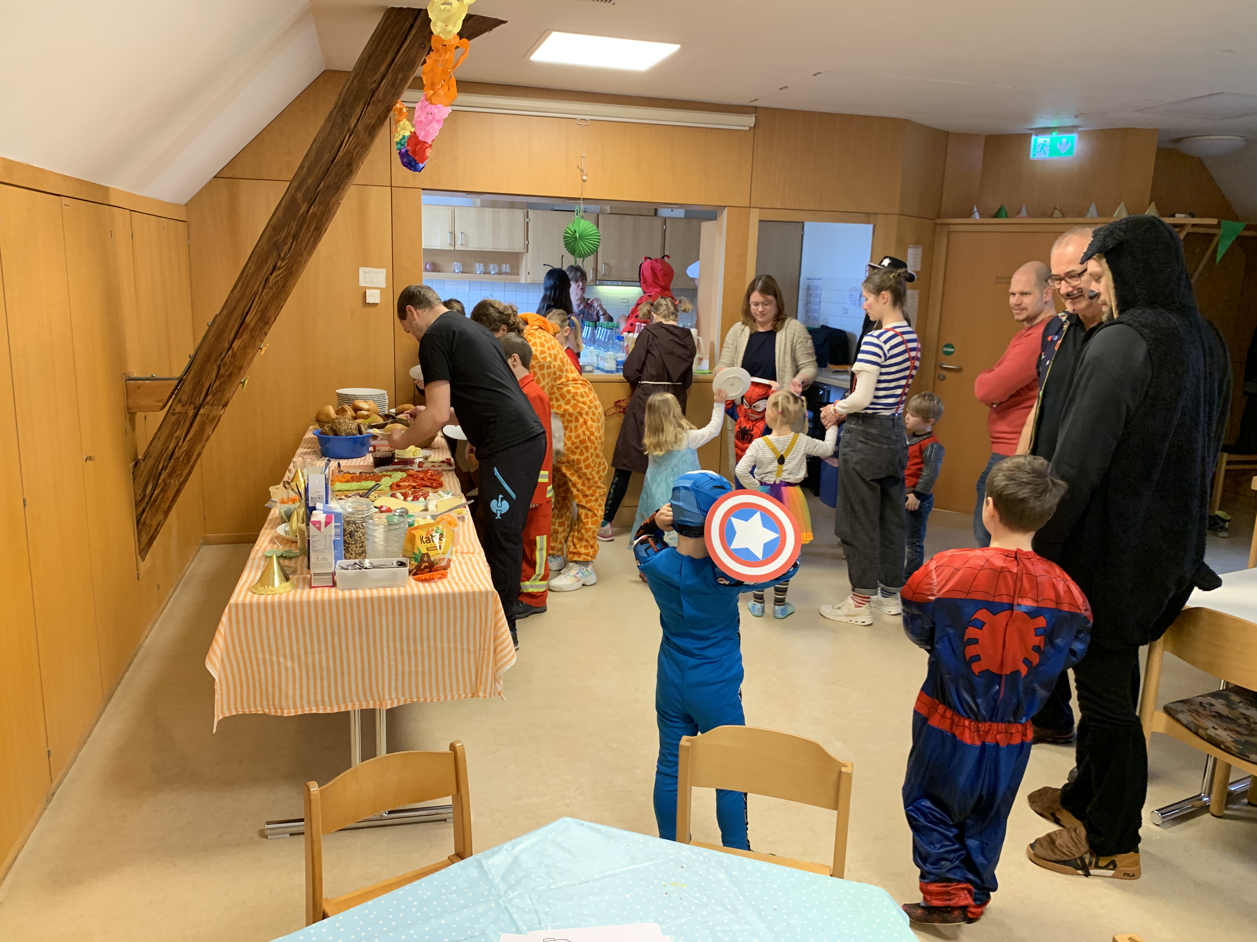 Erwachsene und Kinder stehen am Buffettisch mit Nahrungsmitteln