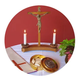 Kreuz mit zwei Kerzen, davor eine Hostienschale