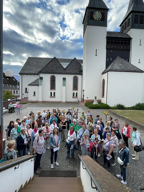 Viele Frauen stehen auf dem Kirchplatz mit einigen geschmückten Kreuzen. Im Hintergrund die St. Anna Kirche