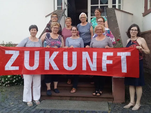 10 Frauen stehen auf der Streppe und halten ein Banner "Zukunft"
